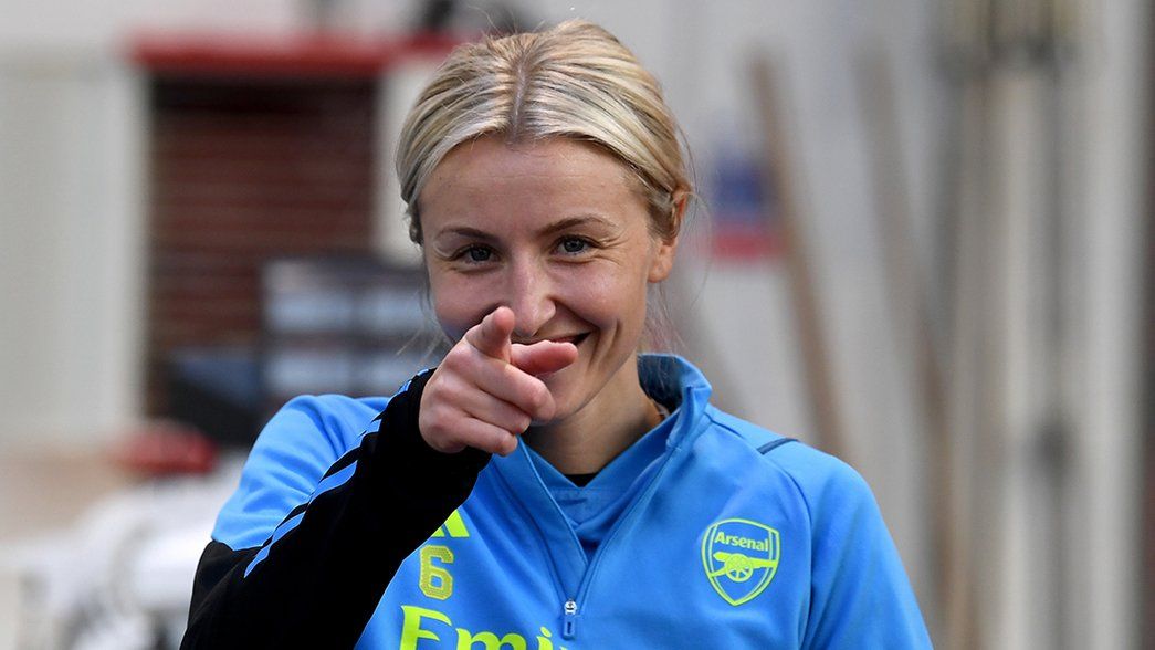 A smiling Leah Williamson points at the camera in the London Colney gym