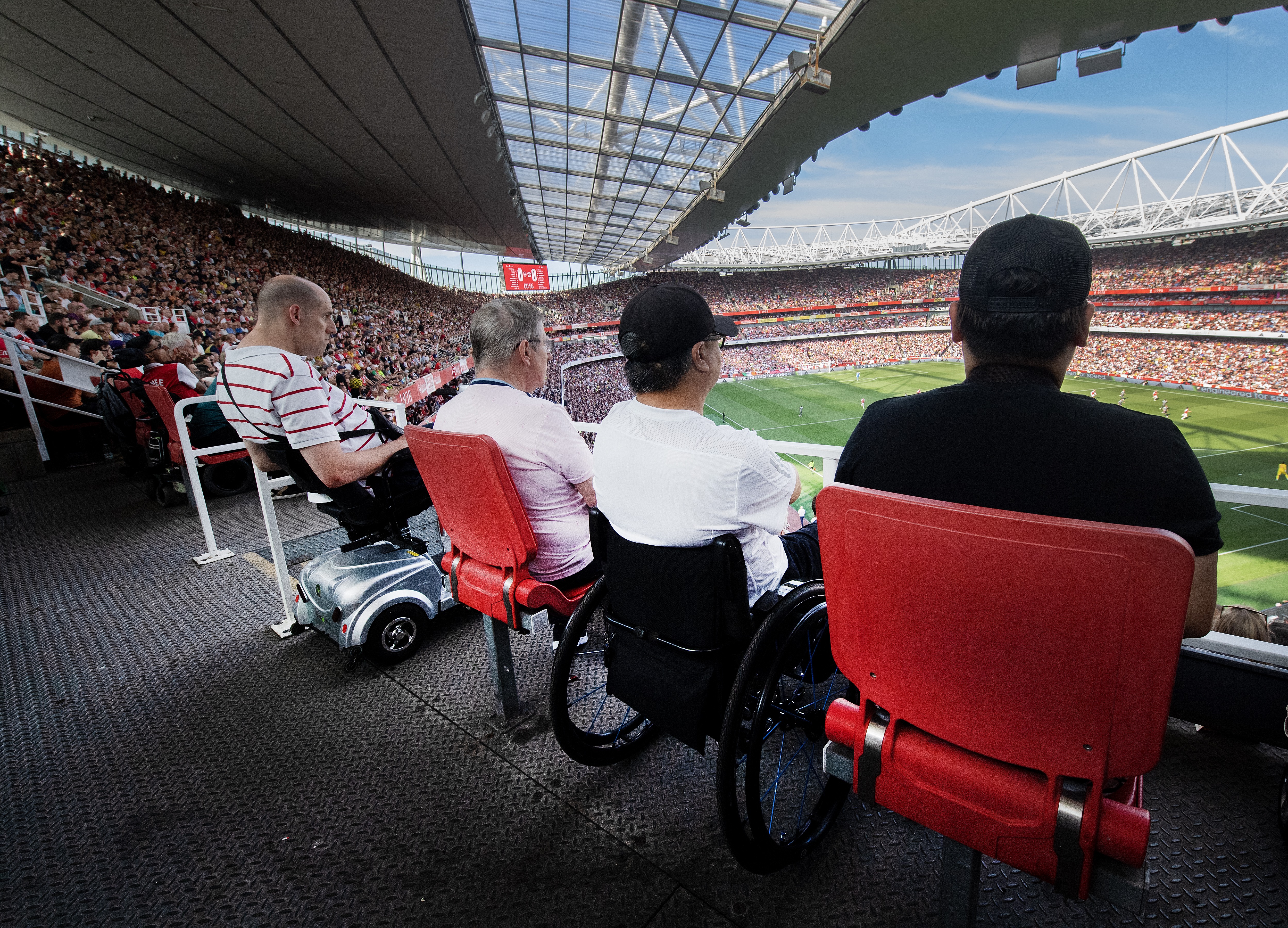 Image showing the view of the pitch from behind supporters on the wheelchair platform in the upper tier
