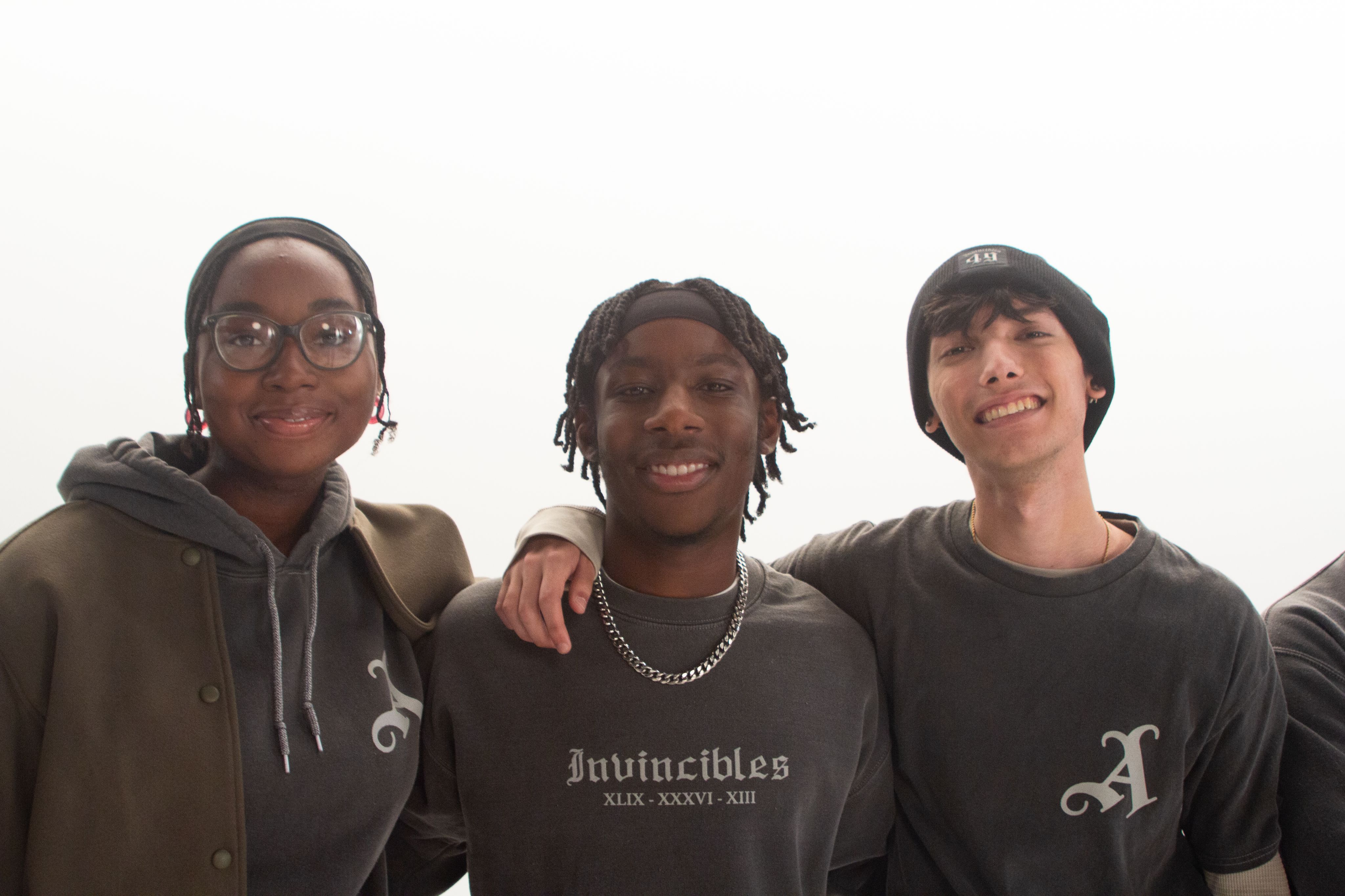 An image of Arsenal supporters modelling the new Invincibles Collection, while smiling with their arms around each other