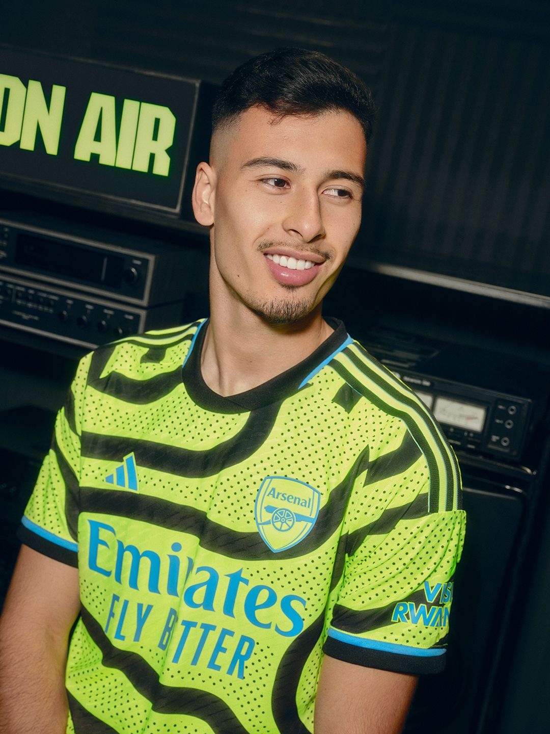 An image of Gabriel Martinelli smiling in front of an 'on air' sign while wearing our new men's team away kit