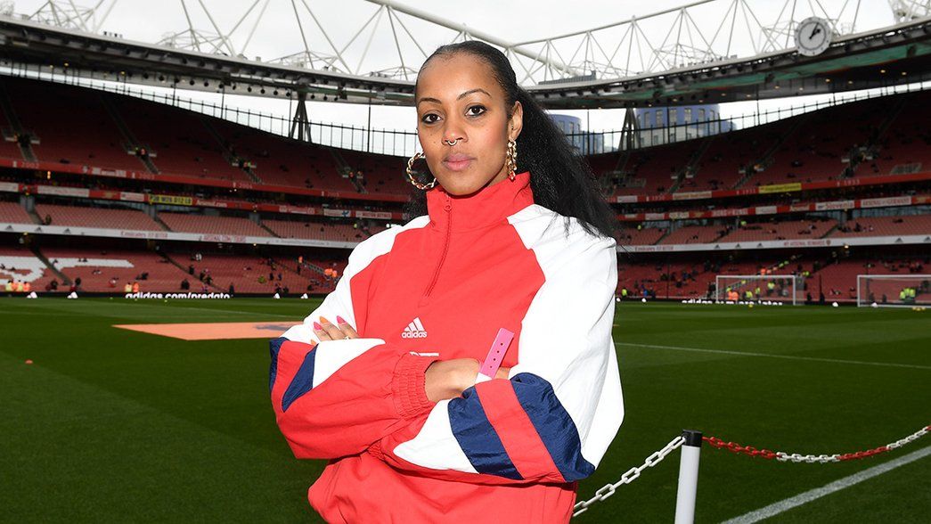 Lou Jasmine stands pitchside at Emirates Stadium with the Clock End in the background