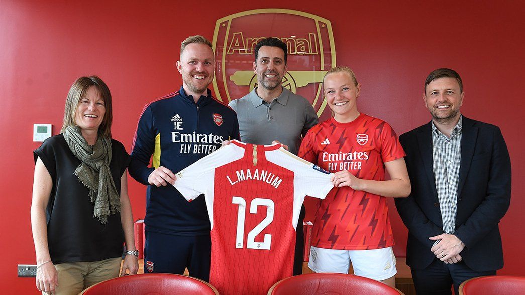 Frida Maanum poses with her new shirt in the Arsenal boardroom, alongside Clare Wheatley, Jonas Eidevall, Edu Gaspar and Richard Garlick