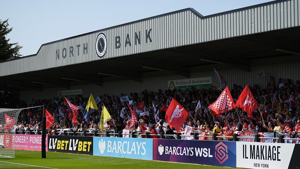 Supporters wave flags in the North Bank at Meadow Park