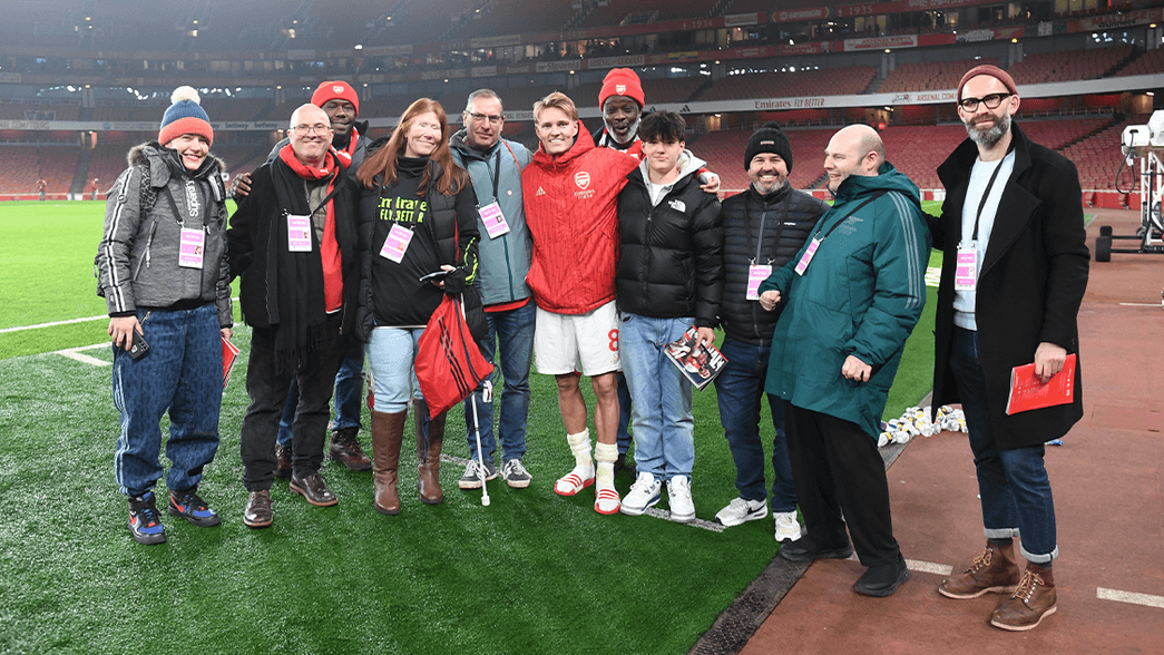A photo containing some blind and partially sighted supporters pitchside at the Emirates Stadium with Martin Odegaard