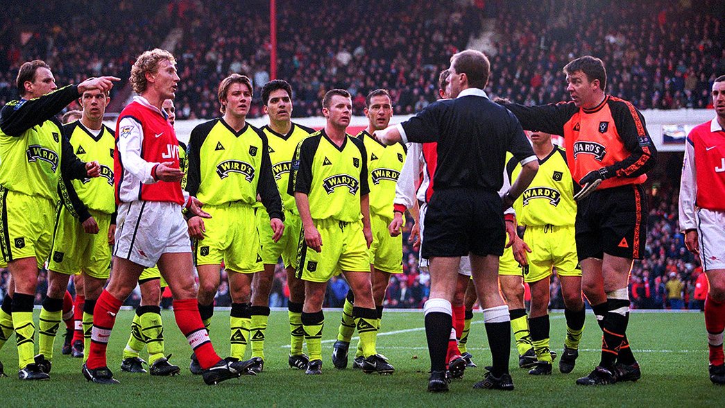 Arsenal players surround referee Peter Jones